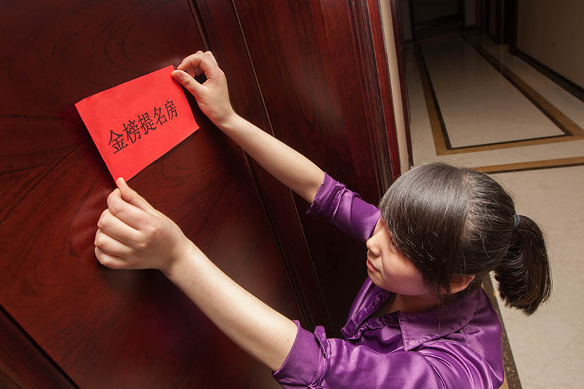 ‘This room brings good luck to pass the exam,’ says the red envelope being stuck to the door of a guest’s room by a hotel staff member, May 30, 2013. Yangguang/VCG