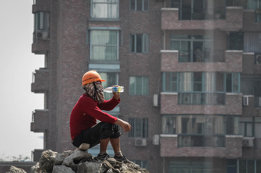 A worker drinks from a water bottle on a construction site in Shanghai, Aug. 7, 2013. Yuan Ding/VCG