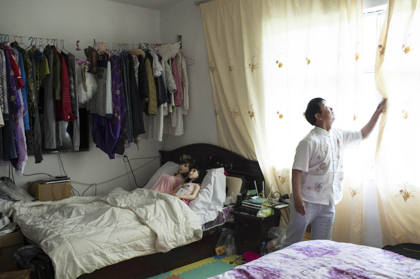 Yu Zhenguo opens a window while his two dolls lie in bed at his villa in Huishui, Guizhou province, May 19, 2016. Xu Haifeng/Sixth Tone