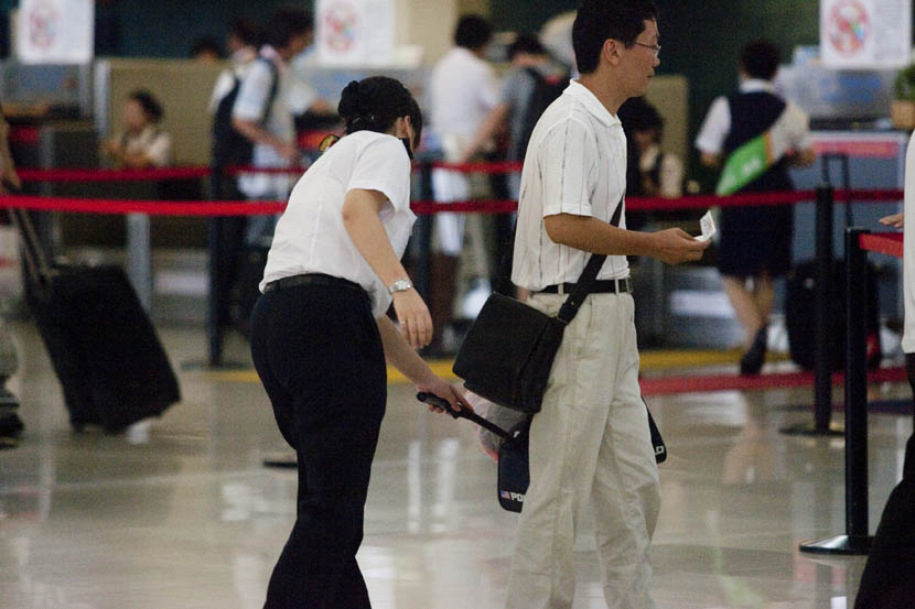 A security officer checks a passenger’s bag using a metal-detecting wand at Shanghai Hongqiao International Airport, Sept. 3, 2009. Zhang Dong/VCG
