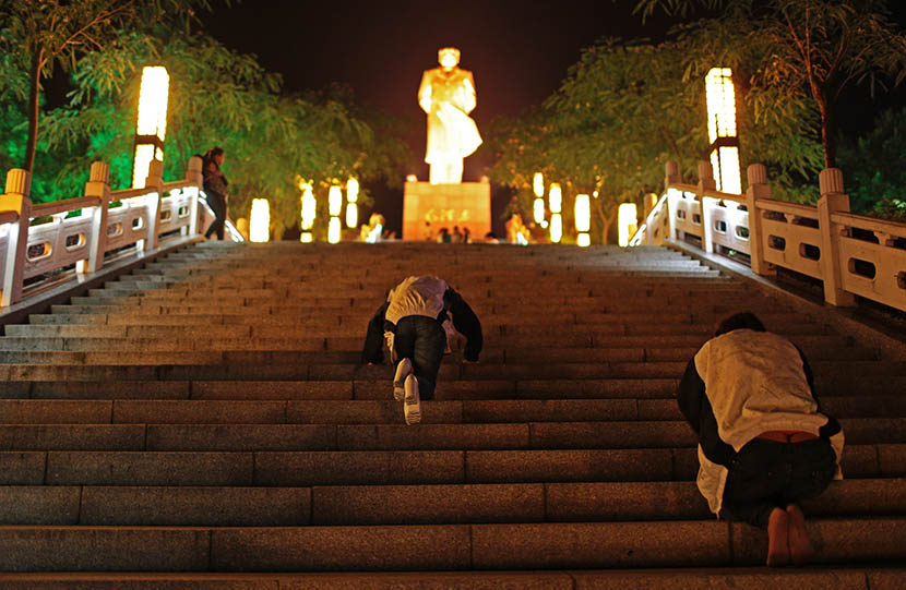Two senior high school students kneel toward a Mao Zedong statue three days before the college entrance examination in Liuan, Anhui province, June 4, 2014. Chen Jie/VCG