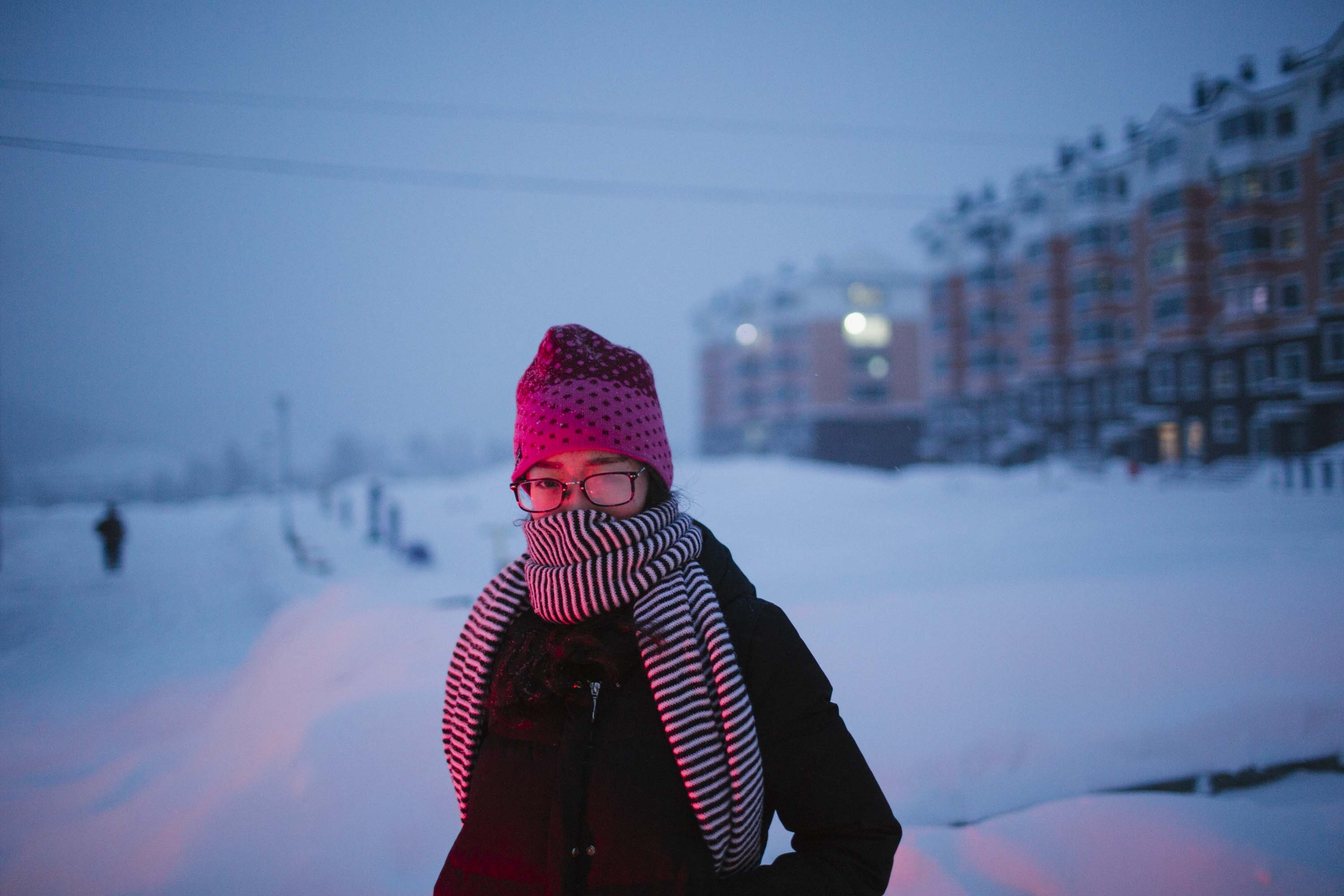 Ru Dongying walks down a snow-covered street in Shuangyashan, in front of recently built apartments, Jan. 19, 2016. Her family’s home once stood here. Zhou Pinglang/Sixth Tone
