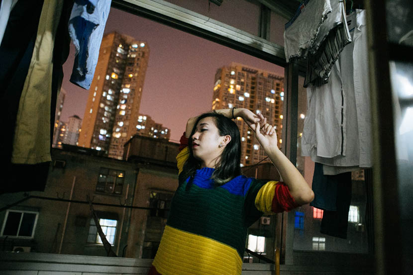 He Xianguo stretches on the balcony of her apartment in Shanghai, April 30, 2016. Jia Yanan/Sixth Tone