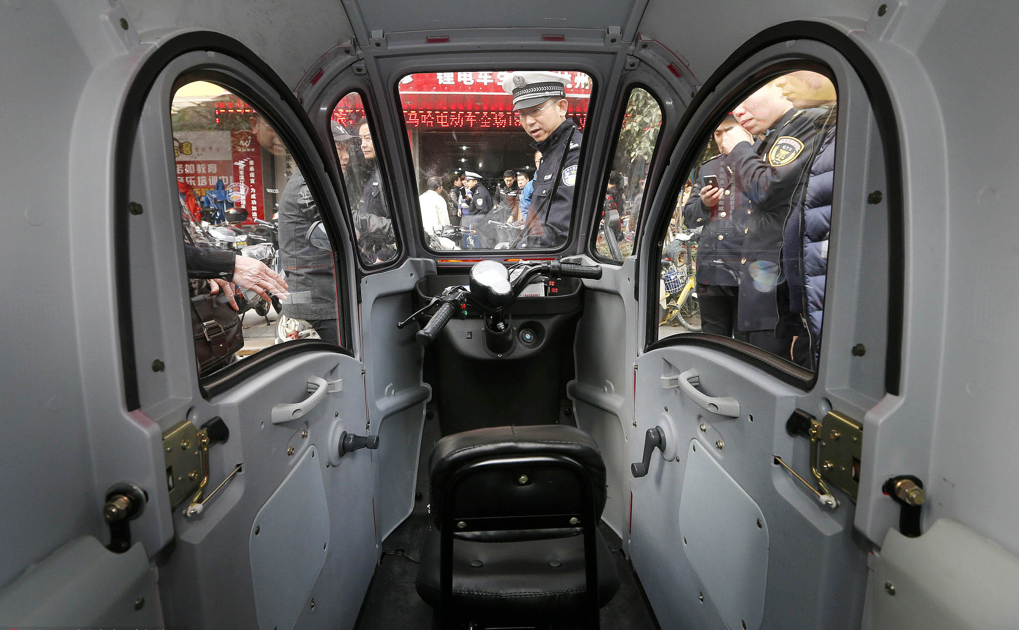 Police inspect an unlicensed electric car in Hangzhou, March 11, 2014. IC