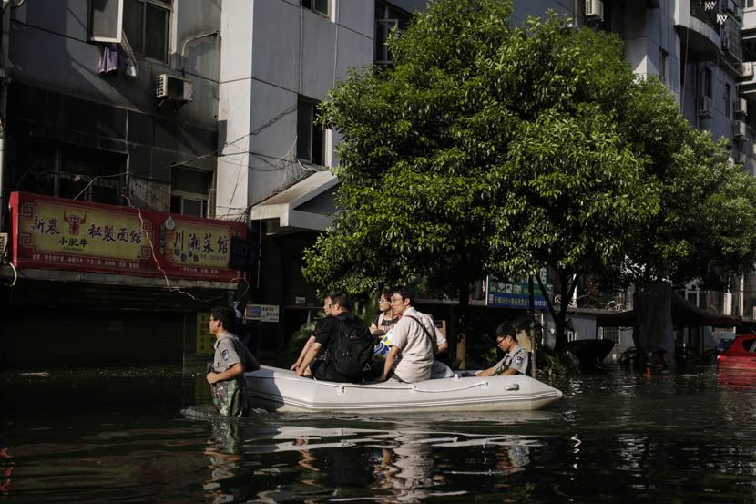 Security guards guide a raft carrying residents of the Nanhu Elegant Garden residental community, Wuhan, Hubei province, July 10, 2016. Han Meng/Sixth Tone