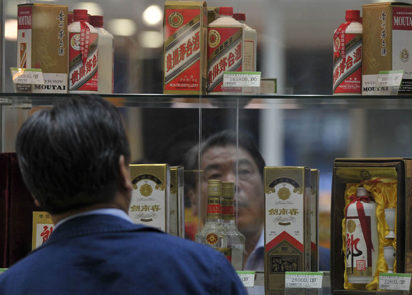A man examines alcohol displayed on a shelf at a shopping mall in Beijing, April 24, 2014. An Xin/VCG
