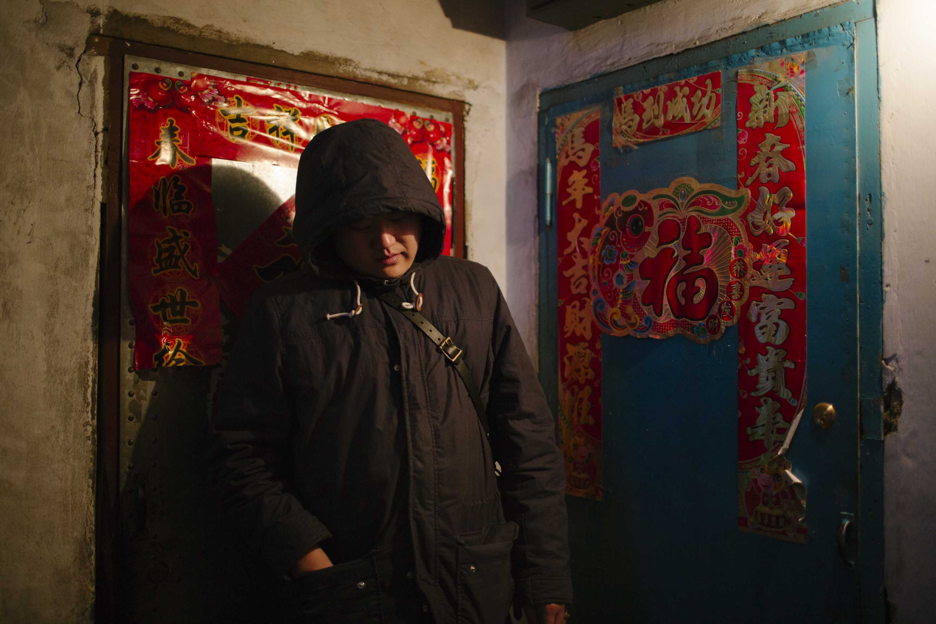 Zhang Tianqi stands beside the door of his grandparents’ apartment in Shuangyashan. The exterior is adorned with the character ‘fu’ — or ‘good fortune,’ Jan. 22, 2016. Zhou Pinglang/Sixth Tone