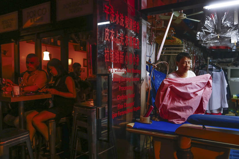 The owner of a dry-cleaning shop works while the crowds outside reach a crescendo at 11 p.m., Shanghai, July 15, 2016. Zhang Ruiqi/IC