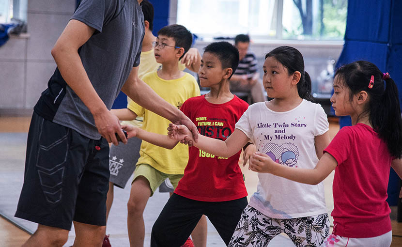 A fencing coach instructs children at the Wang Lei International Fencing Club in Shanghai, Aug. 3, 2016. Zhou Yinan/Sixth Tone