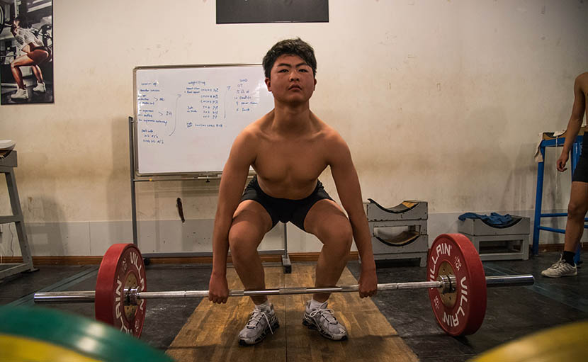A man lifts weights at Venus Weightlifting Club in Shanghai, Aug. 4, 2016. Zhou Yinan/Sixth Tone