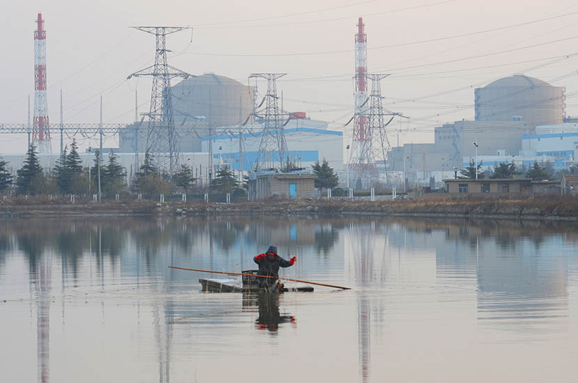 Tianwan Nuclear Power Plant is visible behind a fisherman in Lianyungang, Jiangsu province, Aug. 8, 2016. Geng Yuhe/VCG
