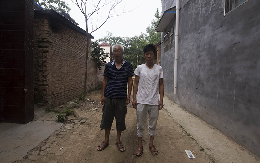 Song Xianzhong poses with his son Song Pengpeng outside their home in Songzhuang, Henan province, Aug. 1, 2016. Owen Churchill/Sixth Tone