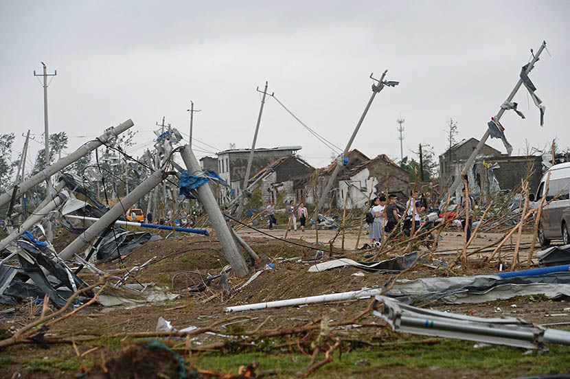 Residents walk along a country road surrounded by wreckage after a tornado hit Funing County, Jiangsu province, June 24, 2016. VCG