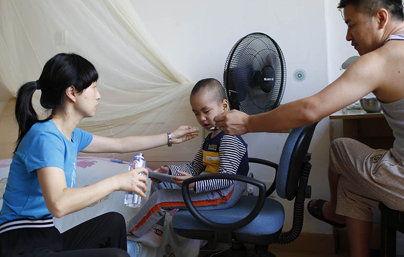 Hao’s parents feed him breakfast and medicine in the morning before their daily trip to the hospital, Shanghai, Aug. 6, 2016. Wu Yue/Sixth Tone