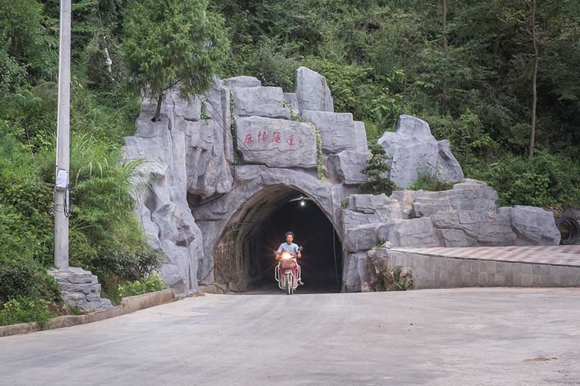 A man rides a motorcycle through the tunnel in Mahuai Village, Guizhou province, Aug. 27, 2016. Denise Hruby/Sixth Tone