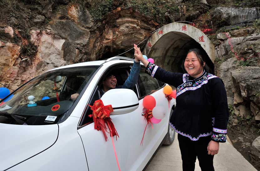 Deng Yingxiang gives a driver a high-five at the entrance to the tunnel in Mahuai Village, Jan. 18, 2016. Xu Fengshan/IC
