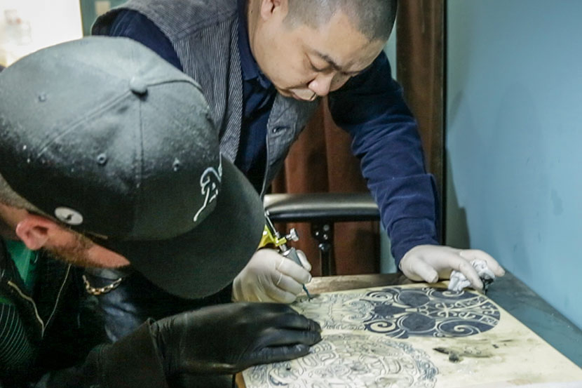 Tattoo artist Shao Gang demonstrates the process of tattooing a pattern to apprentice Daniel Whitford in Shanghai, March 25, 2017. Tang Xiaolan/Sixth Tone