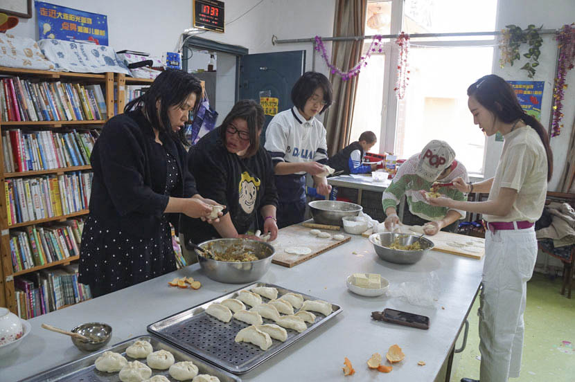 Volunteers make dumplings with the kids at Dalian Children’s Village in Liaoning province, April 17, 2017. Fan Yiying/Sixth Tone
