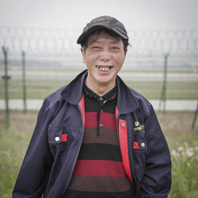 63-year-old Ye Yinggen, a migrant worker from Jiangxi province working on Pudong’s fifth runway, poses for a photo outside Shanghai’s Pudong International Airport, May 5, 2017. Daniel Holmes/Sixth Tone