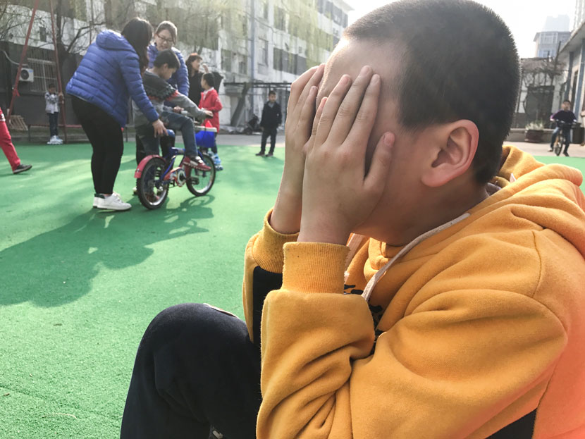 A student covers his face with his hands on the playground at the Lingxing Community Service Center in Taiyuan, Shanxi province, April 5, 2017. Wang Yiwei/Sixth Tone