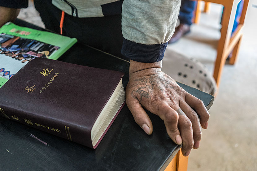 A faded tattoo of a rose can be seen on Cao Yufa’s hand during morning prayers at the Gospel Rehabilitation Center in Baoshan, Yunnan province, March 19, 2017. Thomas Cristofoletti for Sixth Tone