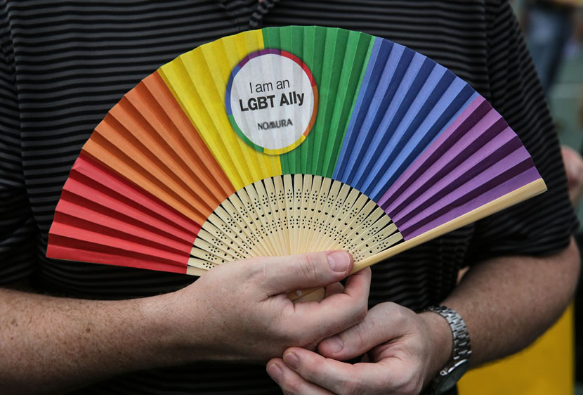 A man holds a rainbow-colored fan during the annual gay pride parade in Hong Kong, Nov. 6, 2015. Isaac Lawrence/VCG