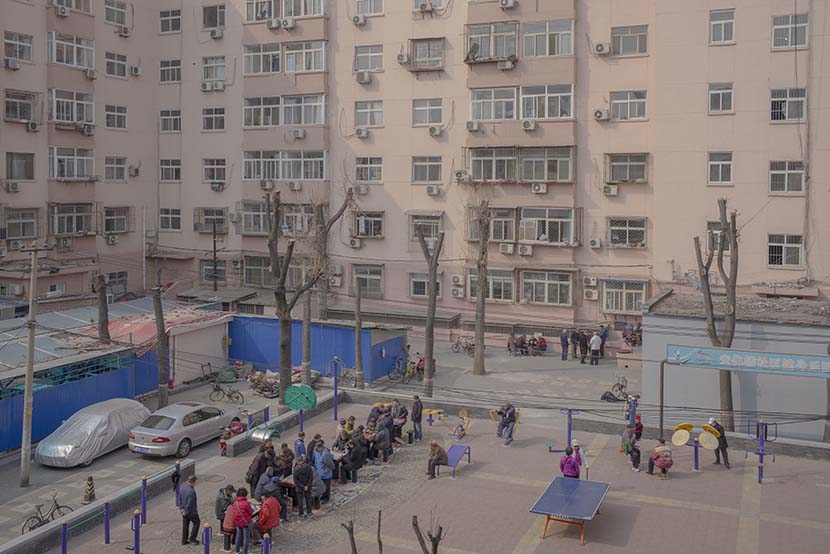 Neighborhood residents play board games in the courtyard behind the Anhua Building in Beijing, March 21, 2018. Wu Yue/Sixth Tone