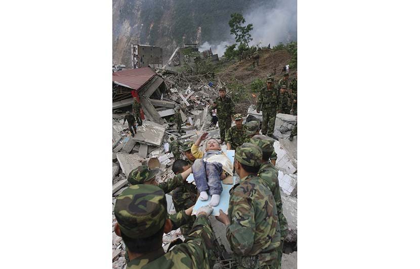 Lang Zheng, lying on a stretcher after being rescued from under a collapsed building, salutes soldiers to express his gratitude, Beichuan Qiang Autonomous County, Sichuan province, May 13, 2008. By Yang Weihua