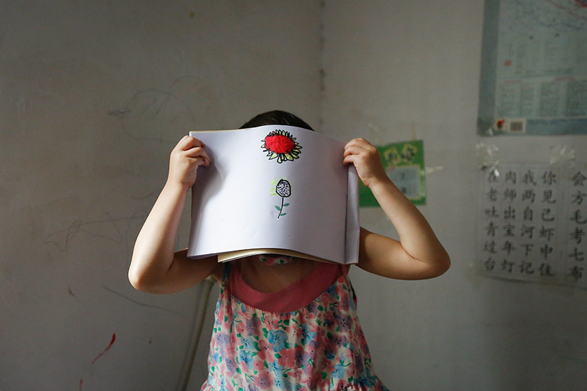 A young sexual abuse victim holds up a drawing at her home in Pingdingshan, Henan province, May 13, 2014. VCG