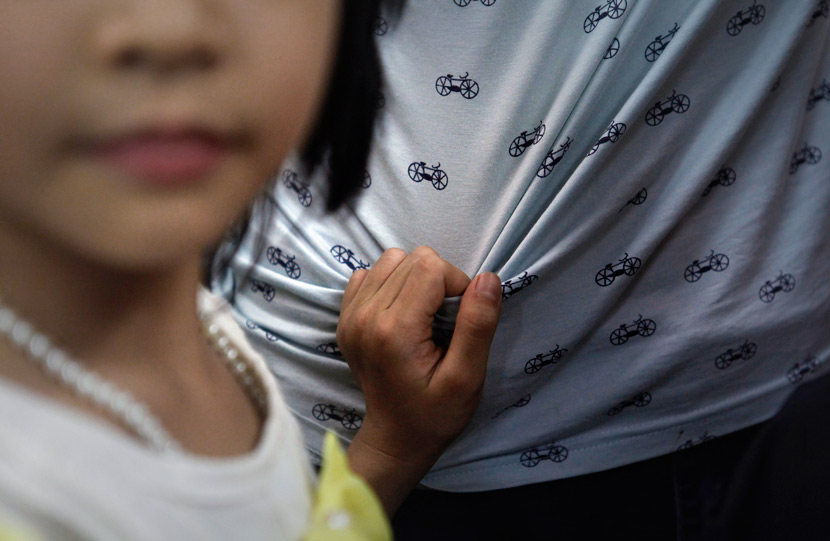 A girl grabs a social worker’s shirt in Foshan, Guangdong province, Aug. 27, 2014. Zhang Mingshu/VCG