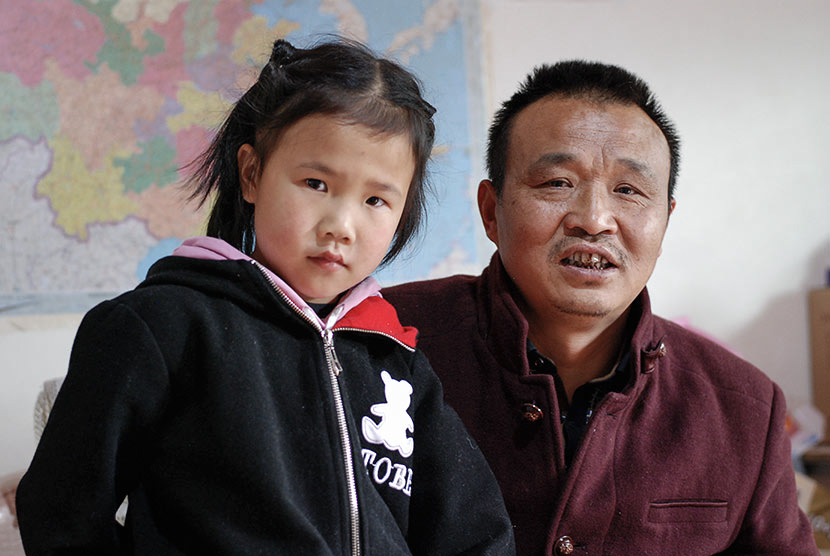 Lu Shihua poses with his 8-year-old daughter, Rui, in Piankou Township, Sichuan province, March 2018. Lu married his second wife, Duan Benju, and had Rui after the earthquake claimed the life of his 16-year-old daughter, Fang. Eileen Guo for Sixth Tone