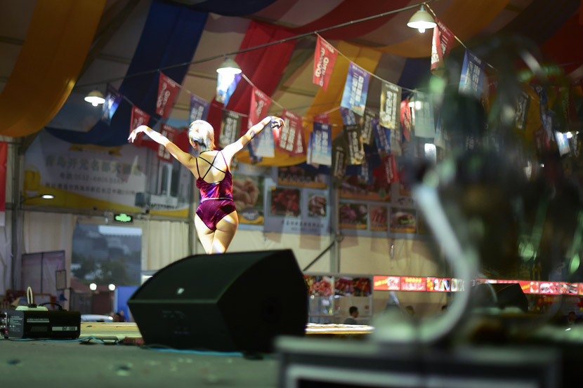 A woman performs inside a tent at a night market in Qingdao, Shandong province, Aug. 10, 2017. VCG