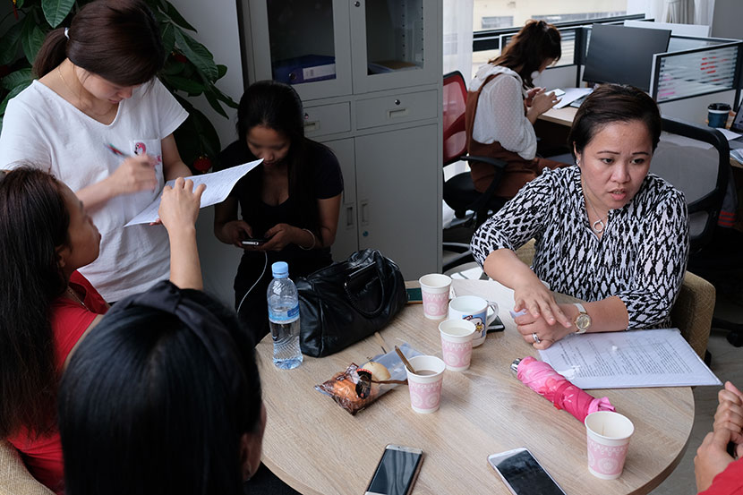 Lalaine Siason and four undocumented Filipina workers discuss the details of an employment contract with an ‘ayi’ agency in Shanghai, May 31, 2018. Nicole Lim for Sixth Tone