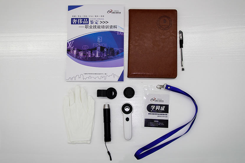 Gloves, flashlight, magnifying glass, textbook, and notebook are neatly arranged on a desk before the luxury good appraisal class in Beijing, May 17, 2018. Courtesy of the Luxury Appraisal Center