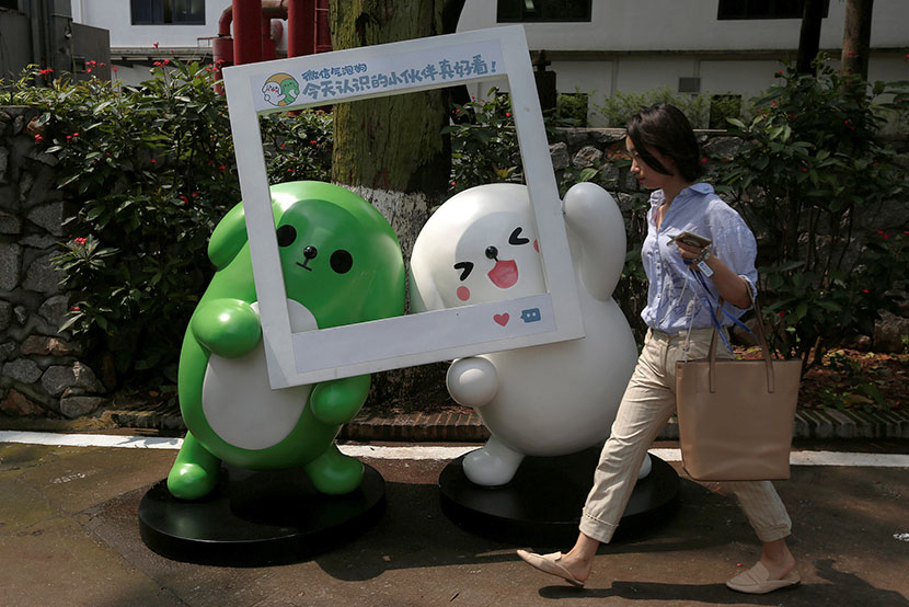 A woman walks past WeChat mascots outside the Tencent office in Guangzhou, Guangdong province, May 9, 2017. Bobby Yip/Reuters/VCG