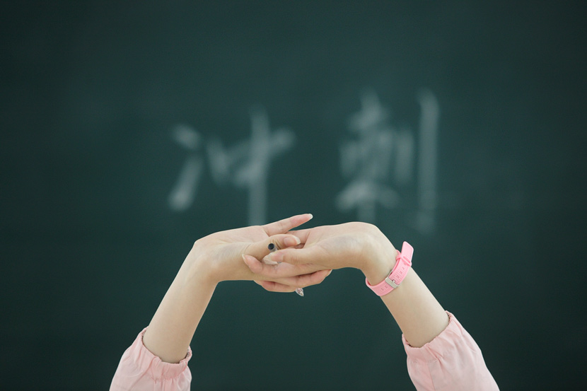 A high school senior stretches in class in Nantong, Jiangsu province, May 21, 2018. The Chinese characters on the blackboard read: ‘sprint.’ Mao Jingsong/VCG