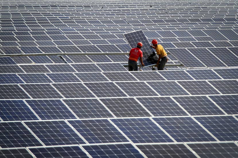 Workers assemble solar panels at a power station in Huaian, Jiangsu province, June 23, 2018. Zhou Changguo/VCG