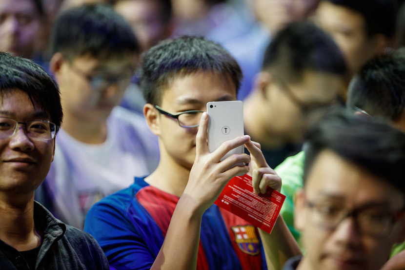 A Smartisan fan takes photos at a product launch in Shanghai, Oct. 18, 2016. VCG