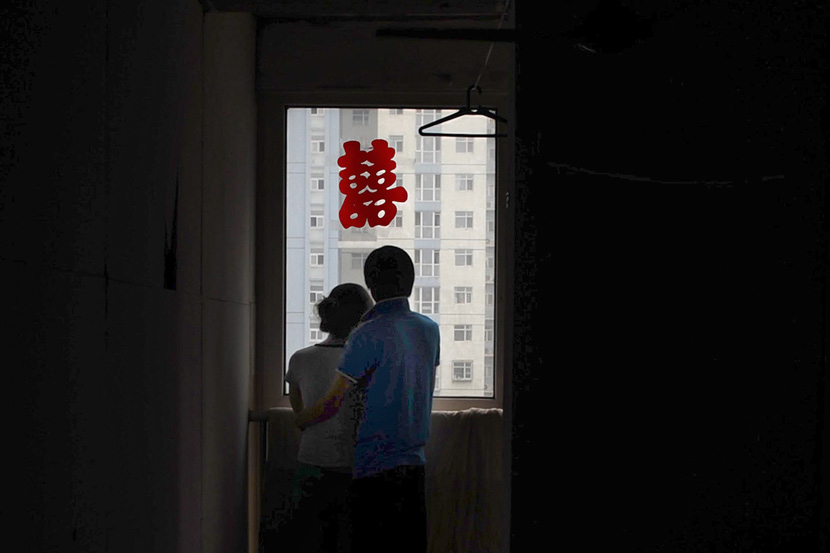 Newlyweds stand by the window at their home in Tianjin, July 26, 2011. Xiao Chunhu/VCG