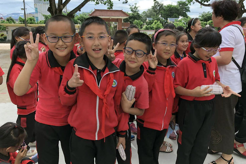 Students pose for a photo after receiving new glasses in Longchuan County, Yunnan province, June 6, 2018. From the Weibo account of Education in Sight