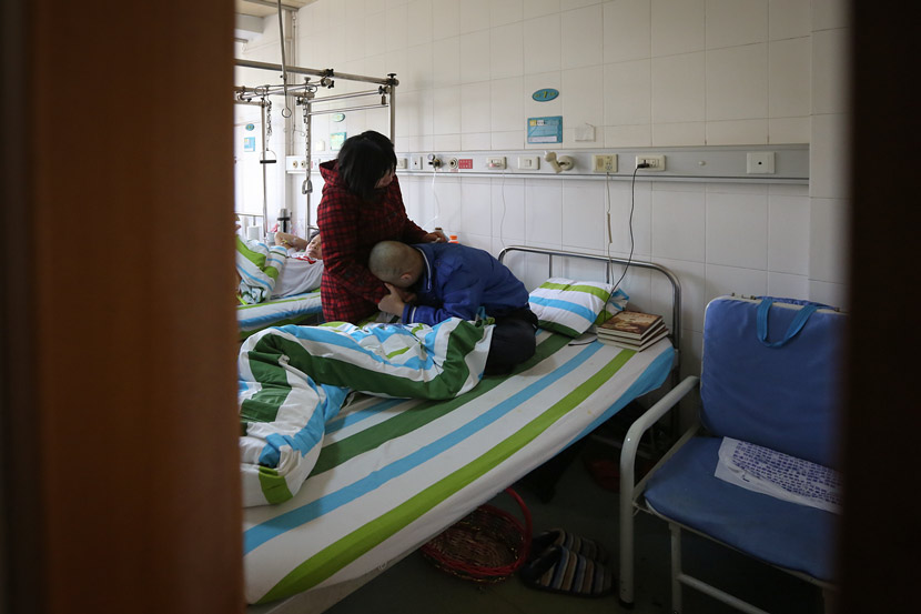 A teenager suffering from bone cancer hugs his mother at a hospital in Xiaogan, Hubei province, April 9, 2015. Ma Luyao/VCG