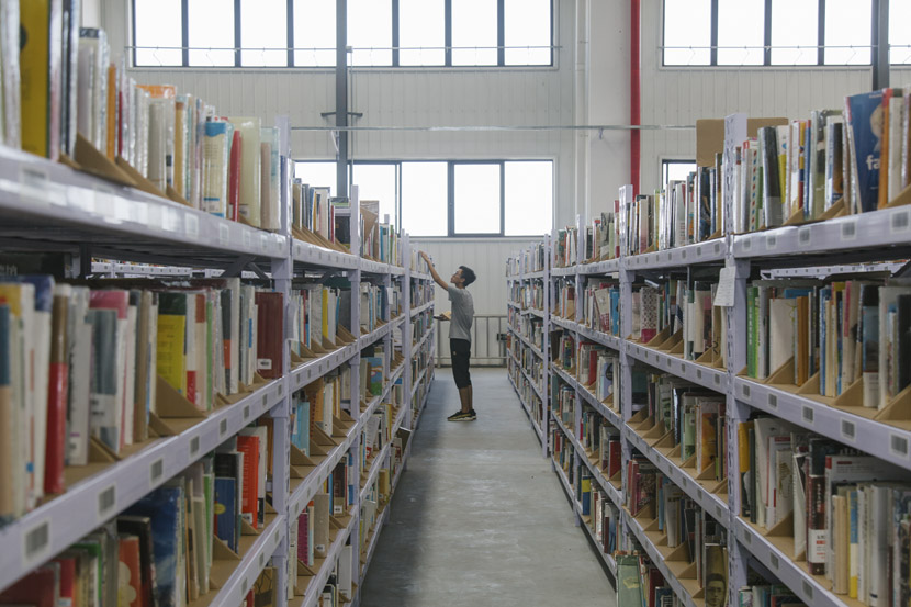 A Déjà Vu employee picks books in the company’s warehouse in Tianjin, July 31, 2018. Wu Huiyuan/Sixth Tone