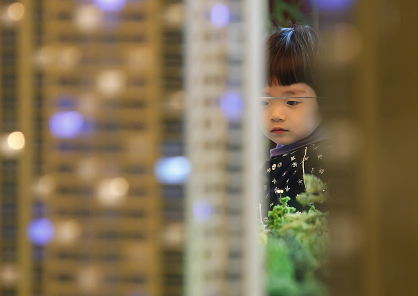 A girl looks at a housing model in a sales office in Changchun, Jilin province, April 23, 2011. Sun Jinglei/VCG