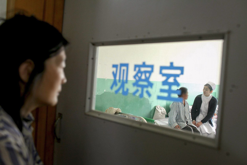 A patient looks on as a nurse talks with another patient at a psychiatric hospital in Anshan, Liaoning province, May 9, 2014. VCG
