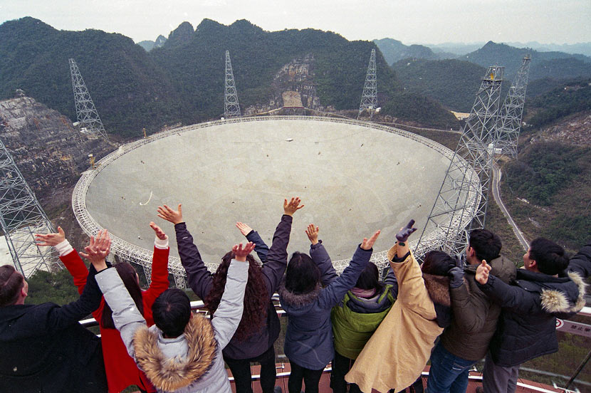 Young people pose for a photo in front of the Five-hundred-meter Aperture Spherical Telescope in Pingtang County, Guizhou province, Jan. 13, 2018. He Junyi/CNS/VCG
