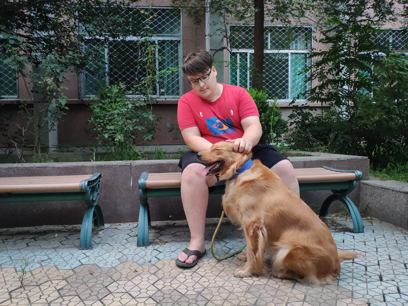 Ken Cari sits on a bench beside his dog, Jenny, in Jinan, Shandong province, Aug. 31, 2018. Fan Yiying/Sixth Tone