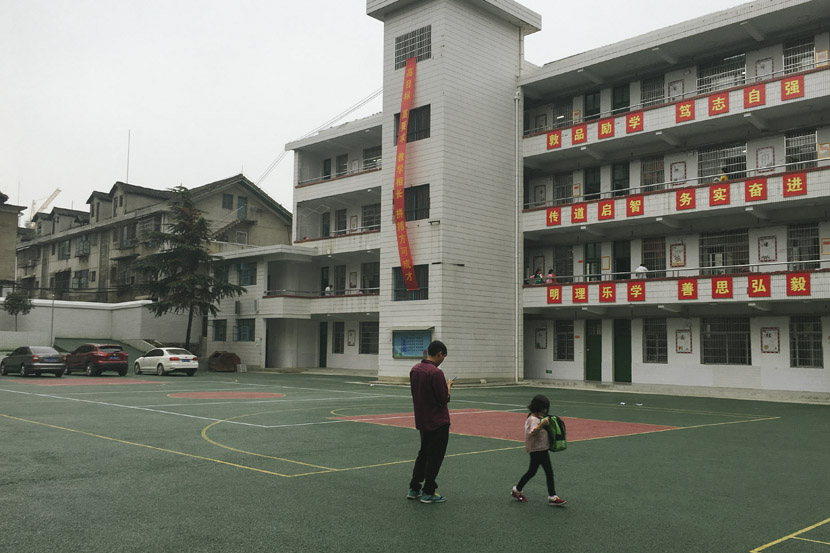 A father and his daughter wait for the girl’s older sibling to finish classes at the newly built Xinhua Experimental Middle School in Xinhua County, Hunan province, Sept. 25, 2018. Ni Dandan/Sixth Tone