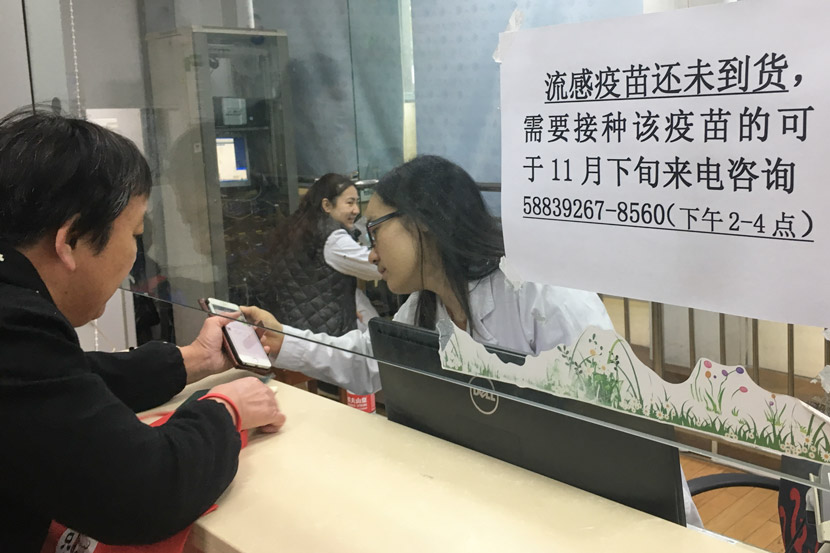A woman asks a staff member about a flu vaccine at a community health service center in Pudong District, Shanghai, Nov. 9, 2018. Ni Dandan/Sixth Tone