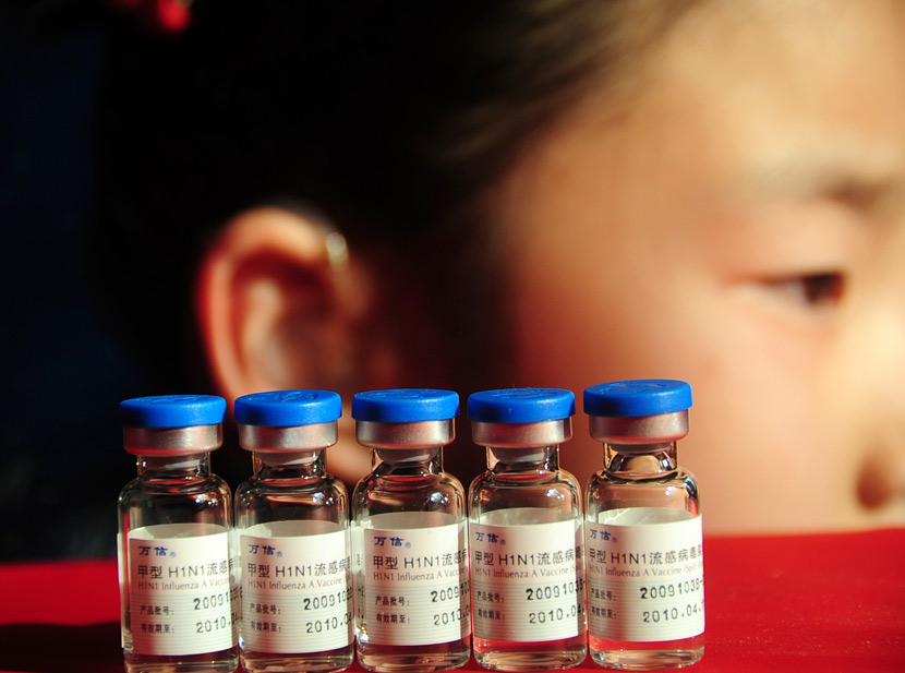 Vials of a flu vaccine rest on a table in front of a student in Jinan, Shandong province, Dec. 23, 2009. VCG
