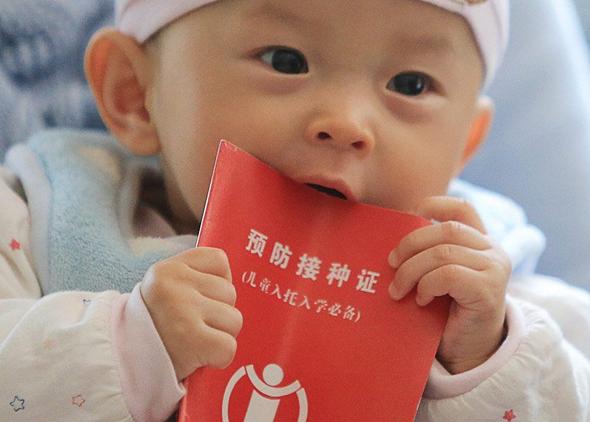 An infant chews on a vaccination record booklet at a health service center in Liuzhou, Guangxi Zhuang Autonomous Region, April 26, 2013. Tan Kaixing/VCG